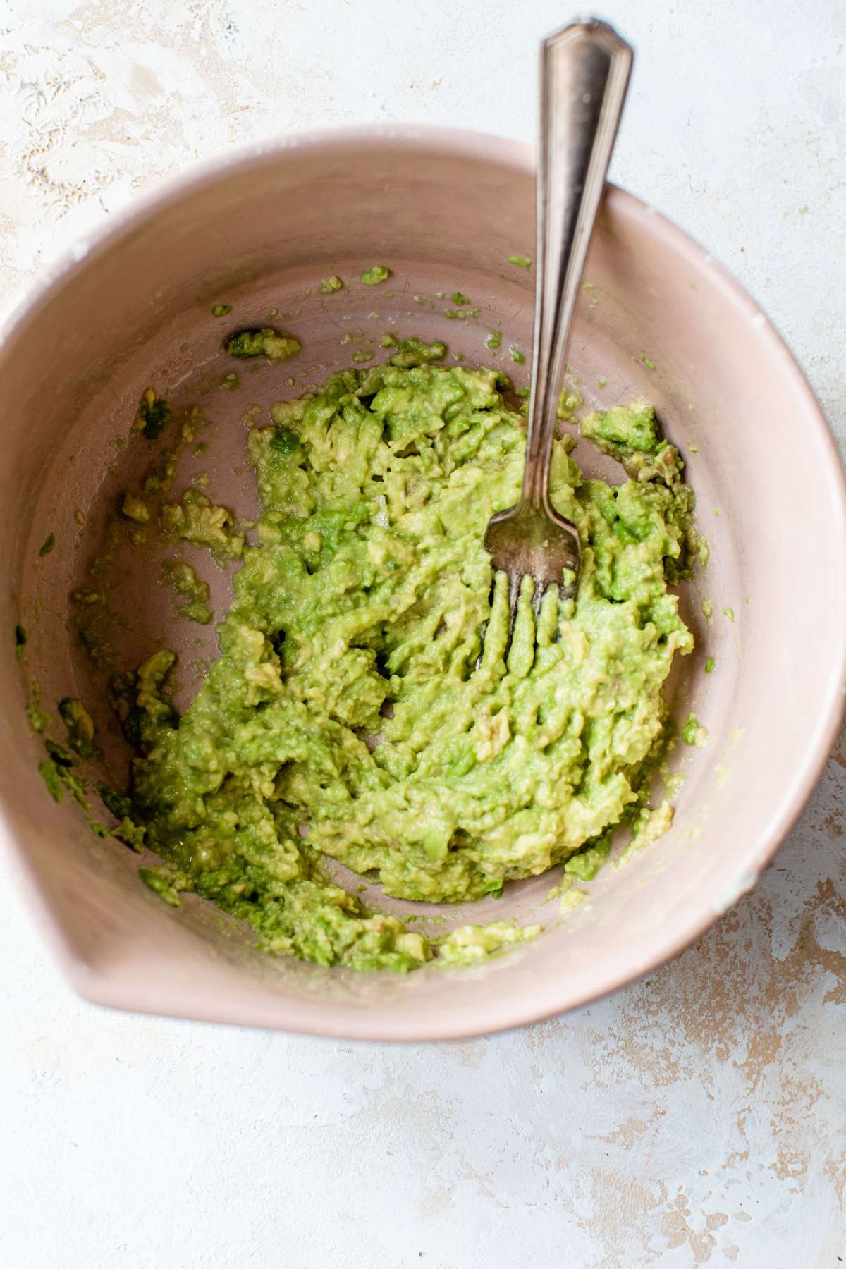 Mashing an avocado with a fork in a large.