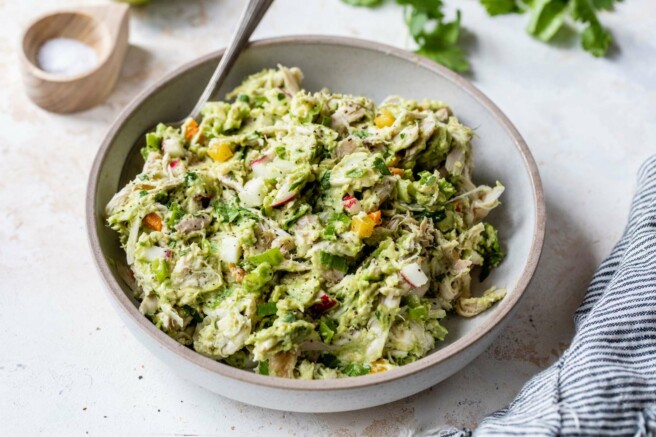 Avocado chicken salad in a bowl with a large serving spoon.