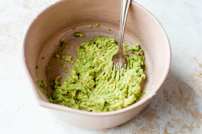Mashing an avocado with a fork in a large.