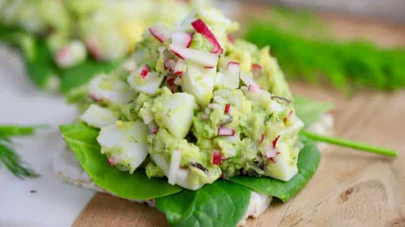 avocado egg salad with fresh radish on top of a bed of spinach and toast square