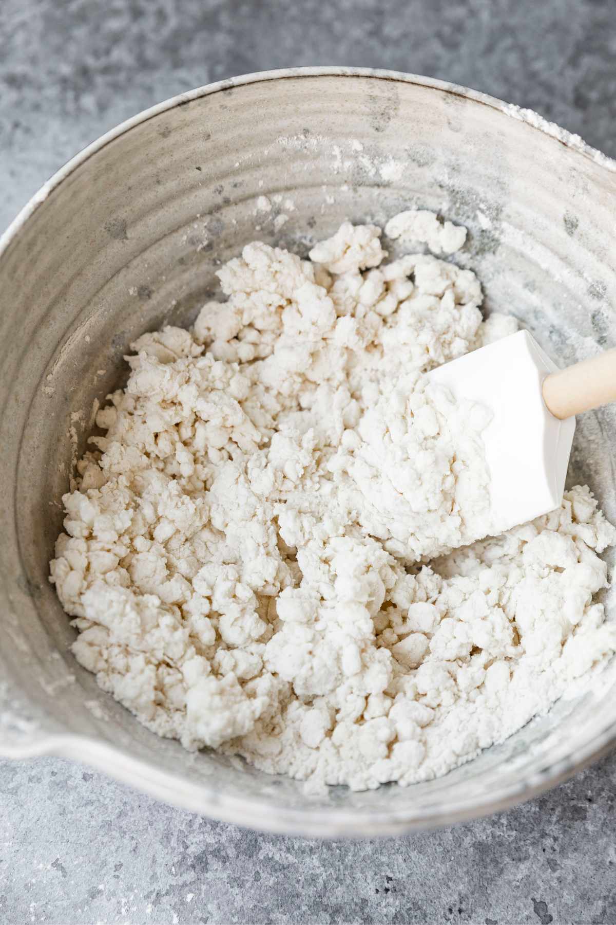 Using a rubber spatula to stir the cottage cheese into the flour mixture.