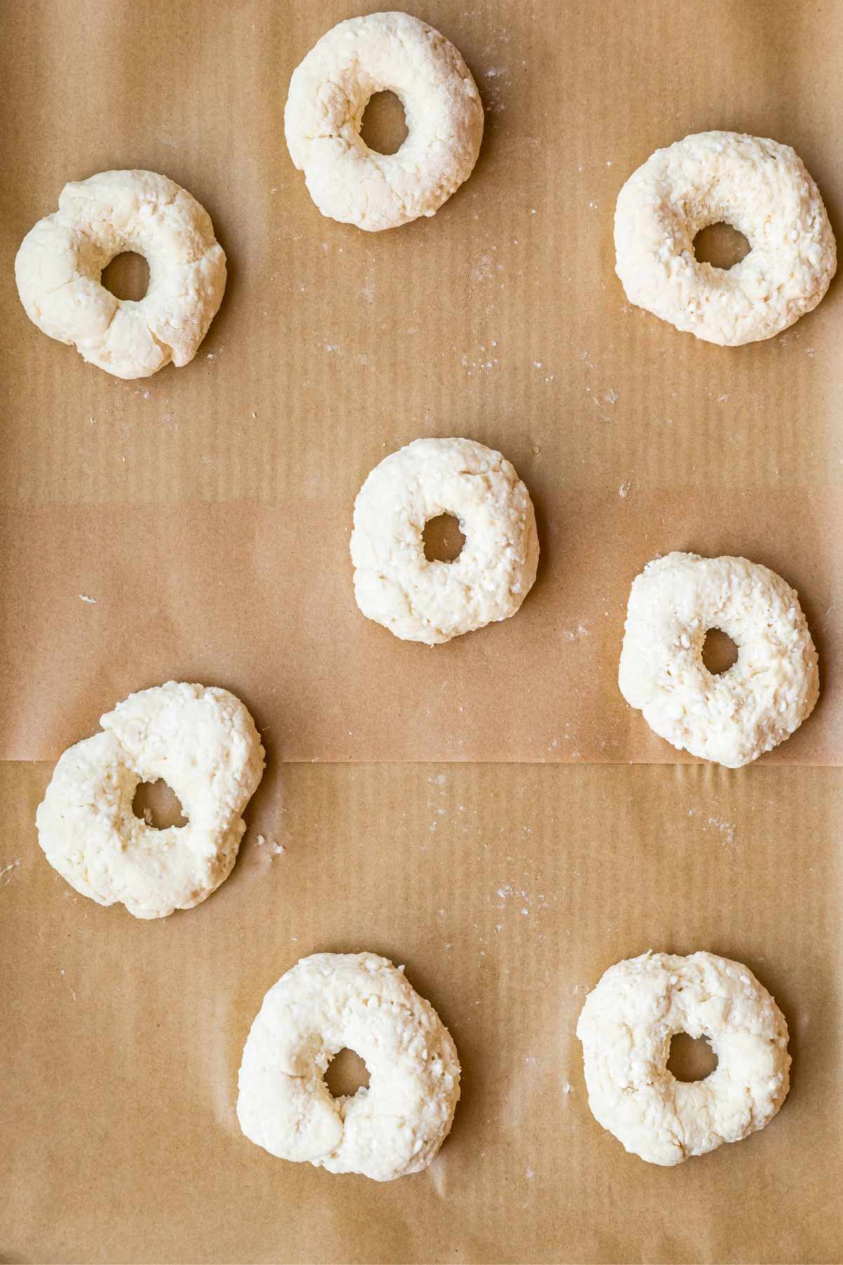 Dough that's shaped into a bagel on parchment paper.