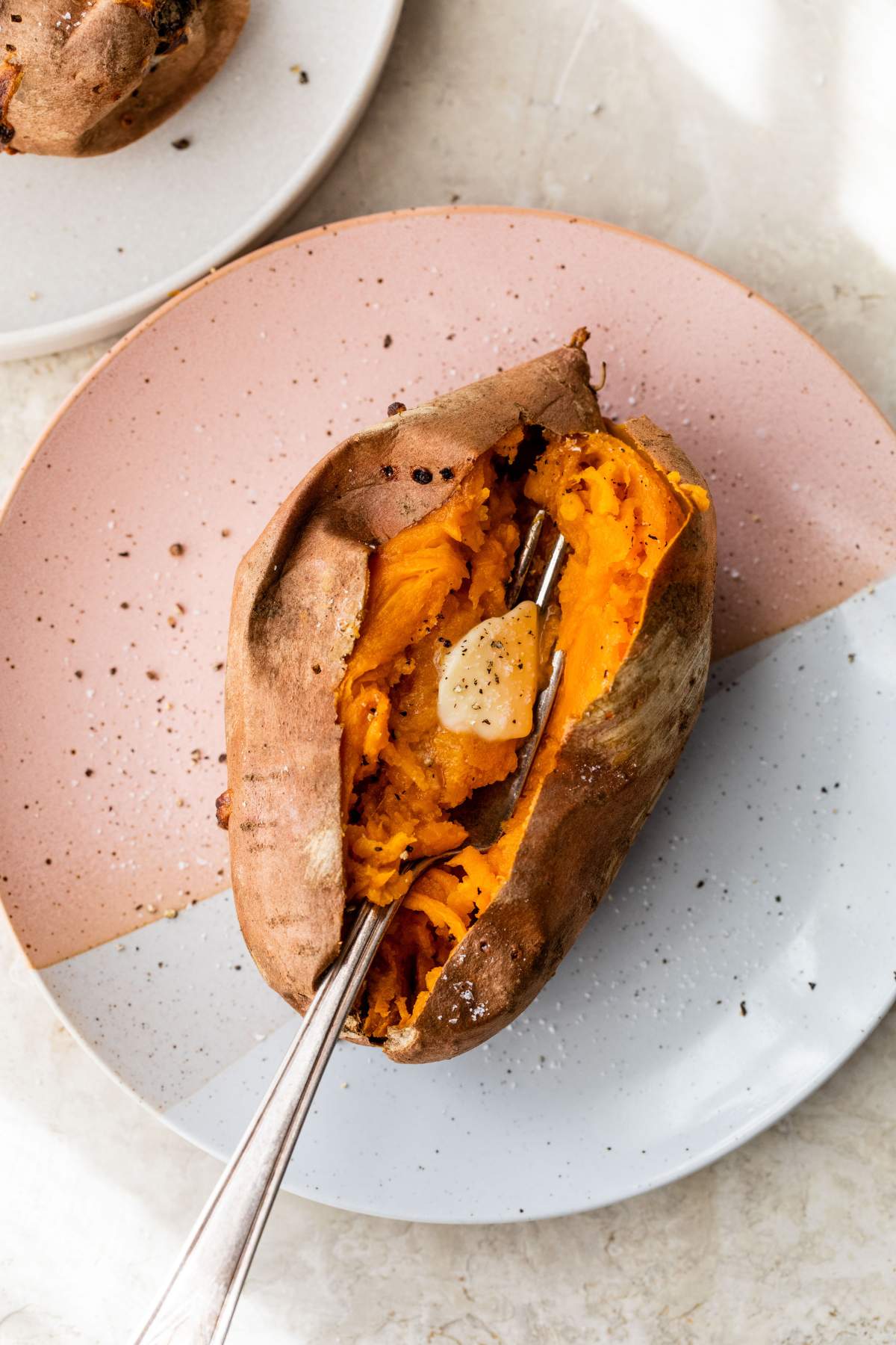 A fork in a sweet potato on a plate.