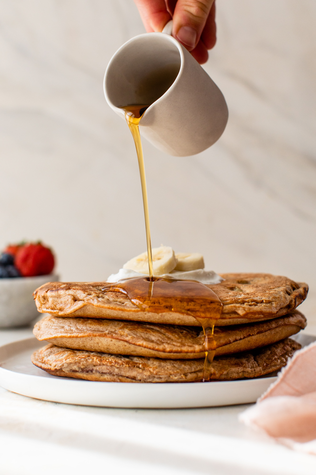maple syrup poured over a stack of peanut butter protein pancakes