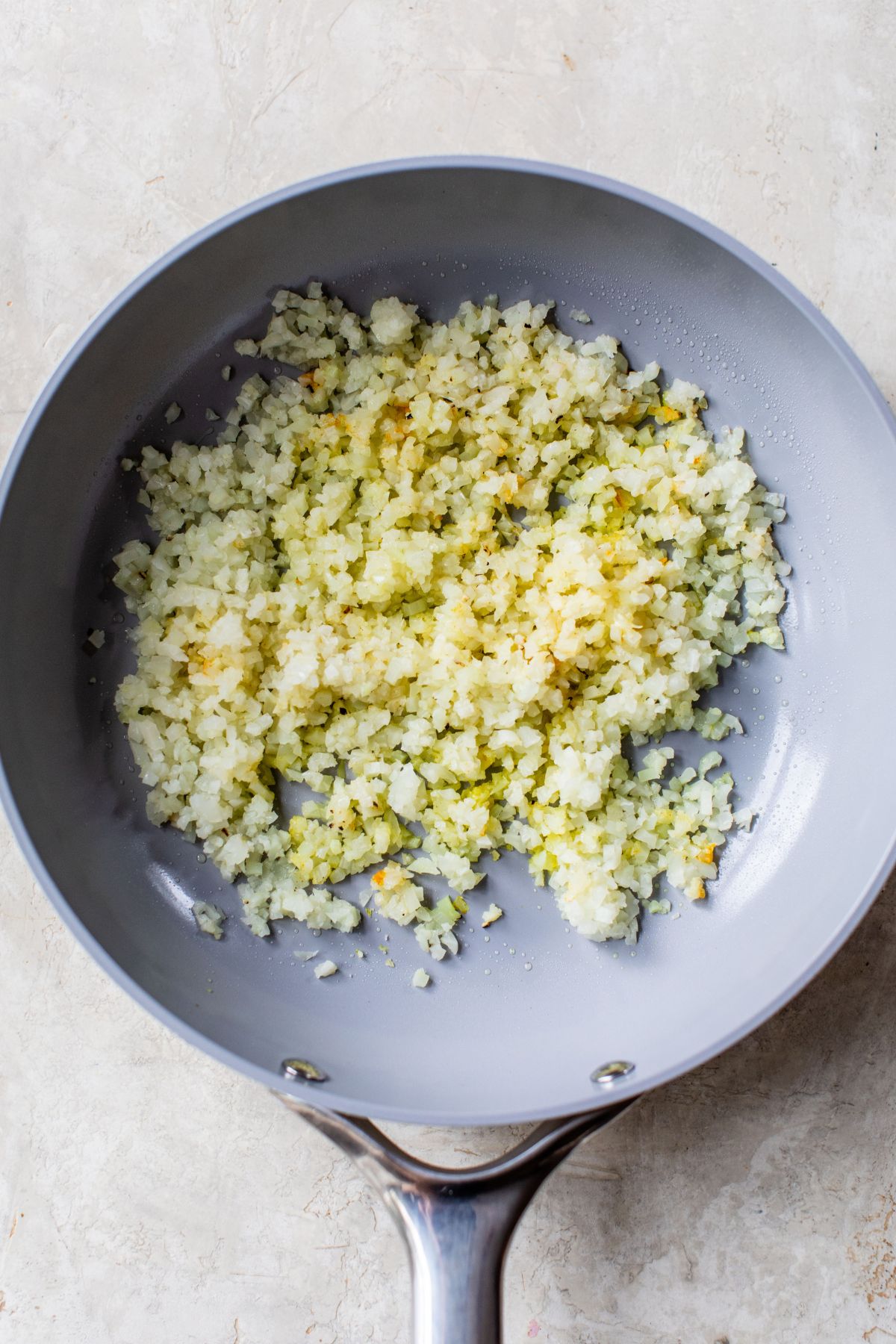 Cooking riced cauliflower in a skillet.