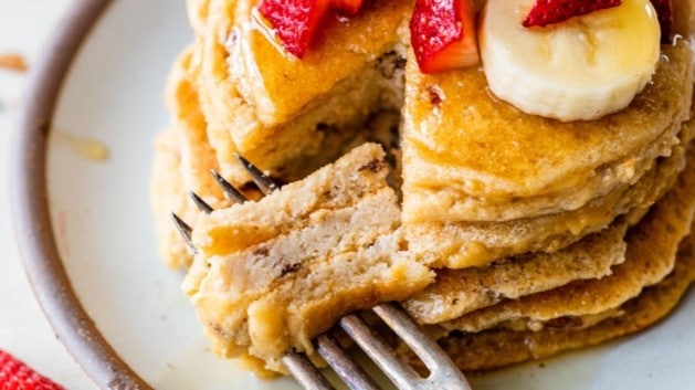 stack of pancakes topped with fresh fruit