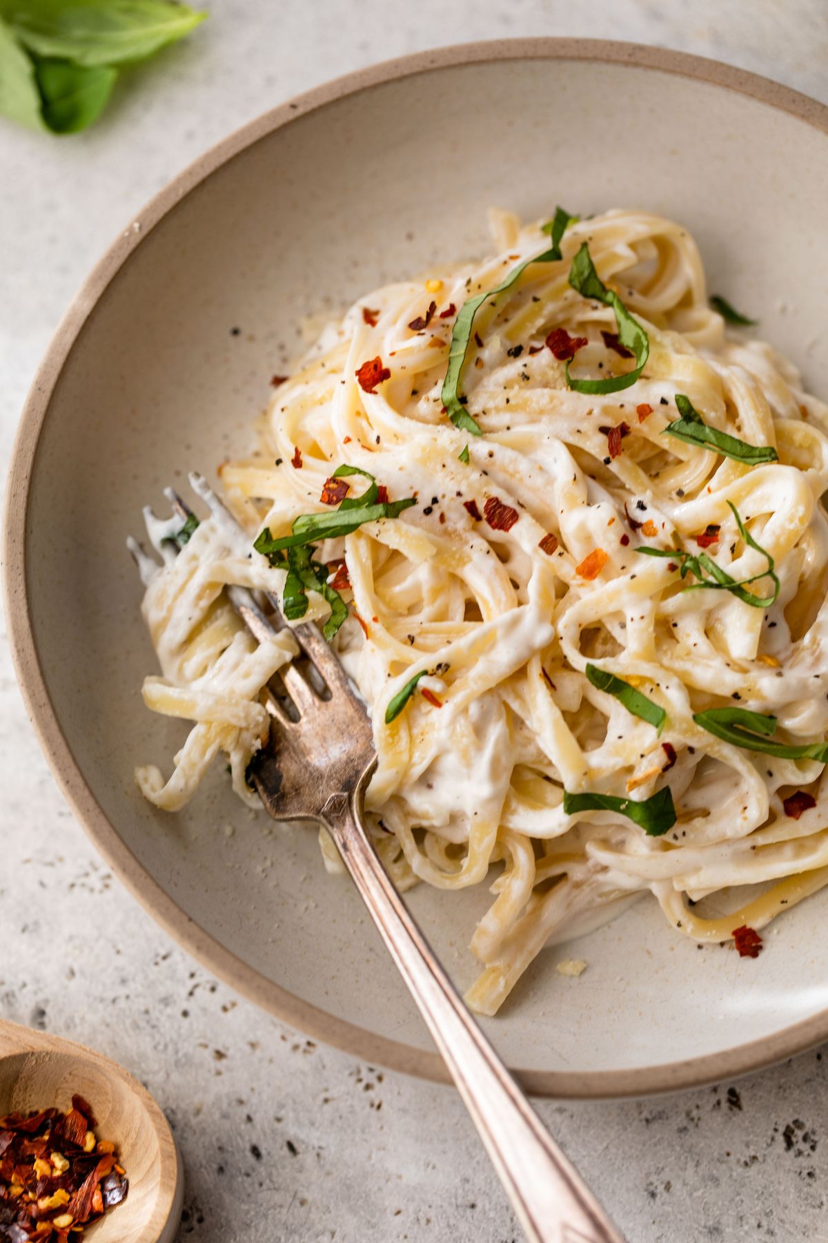 Pasta with Alfredo and garnished with fresh basil and red pepper flakes.