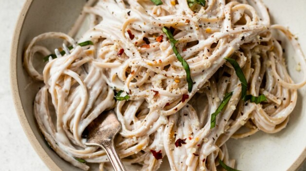 Alfredo made with cottage cheese served over whole grain linguine on a plate with a fork.