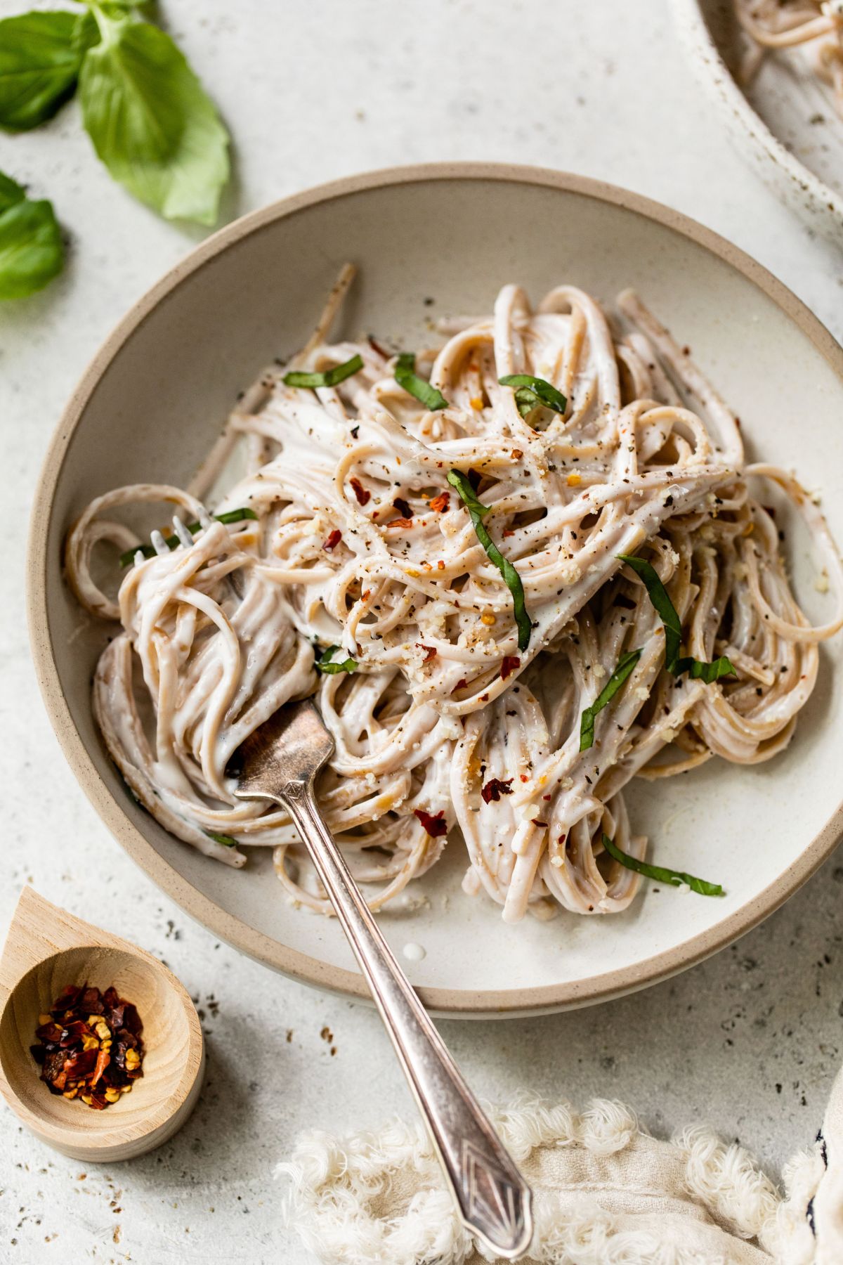 Alfredo made with cottage cheese served over whole grain linguine on a plate with a fork.