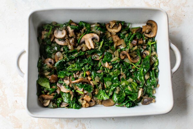 Spinach and mushrooms in the bottom of a casserole dish.