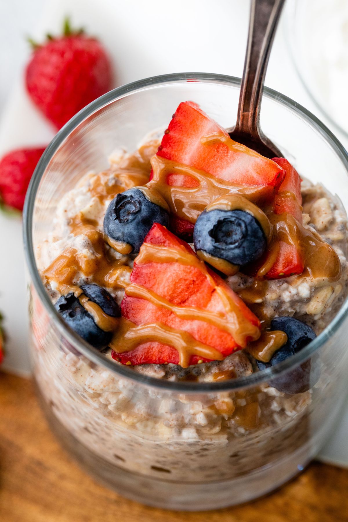 Overnight oats with cottage cheese in glass topped with blueberries and strawberries.