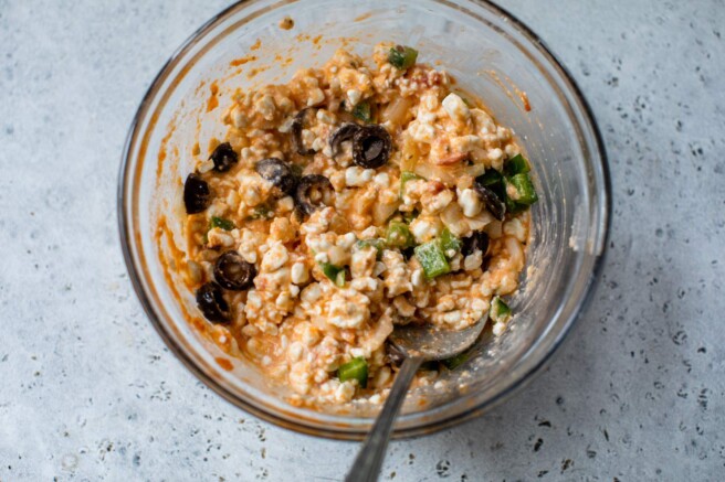Stirring cottage cheese with marinara and mozzarella.