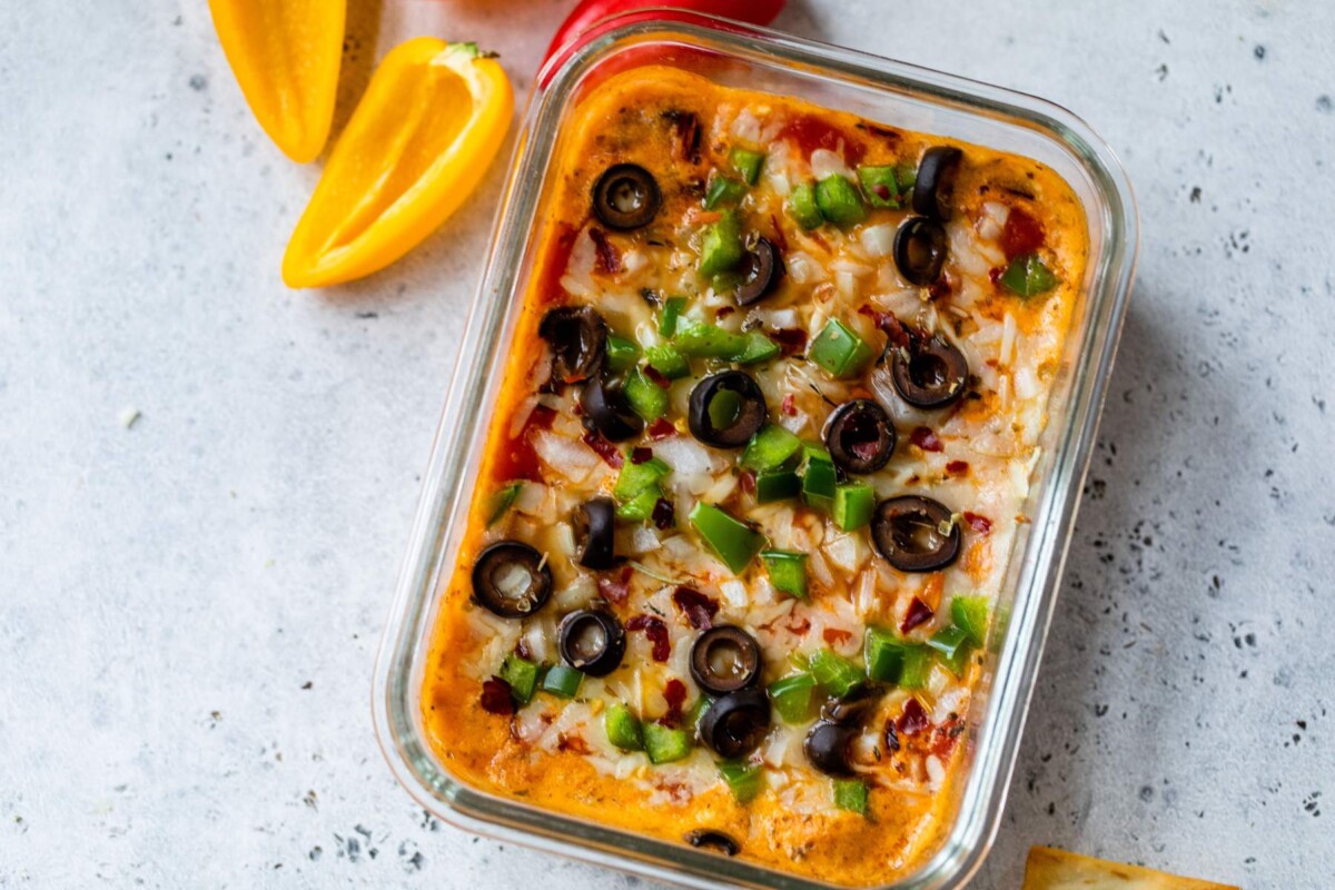 Cottage cheese pizza bowl topped with black olives and green bell peppers.