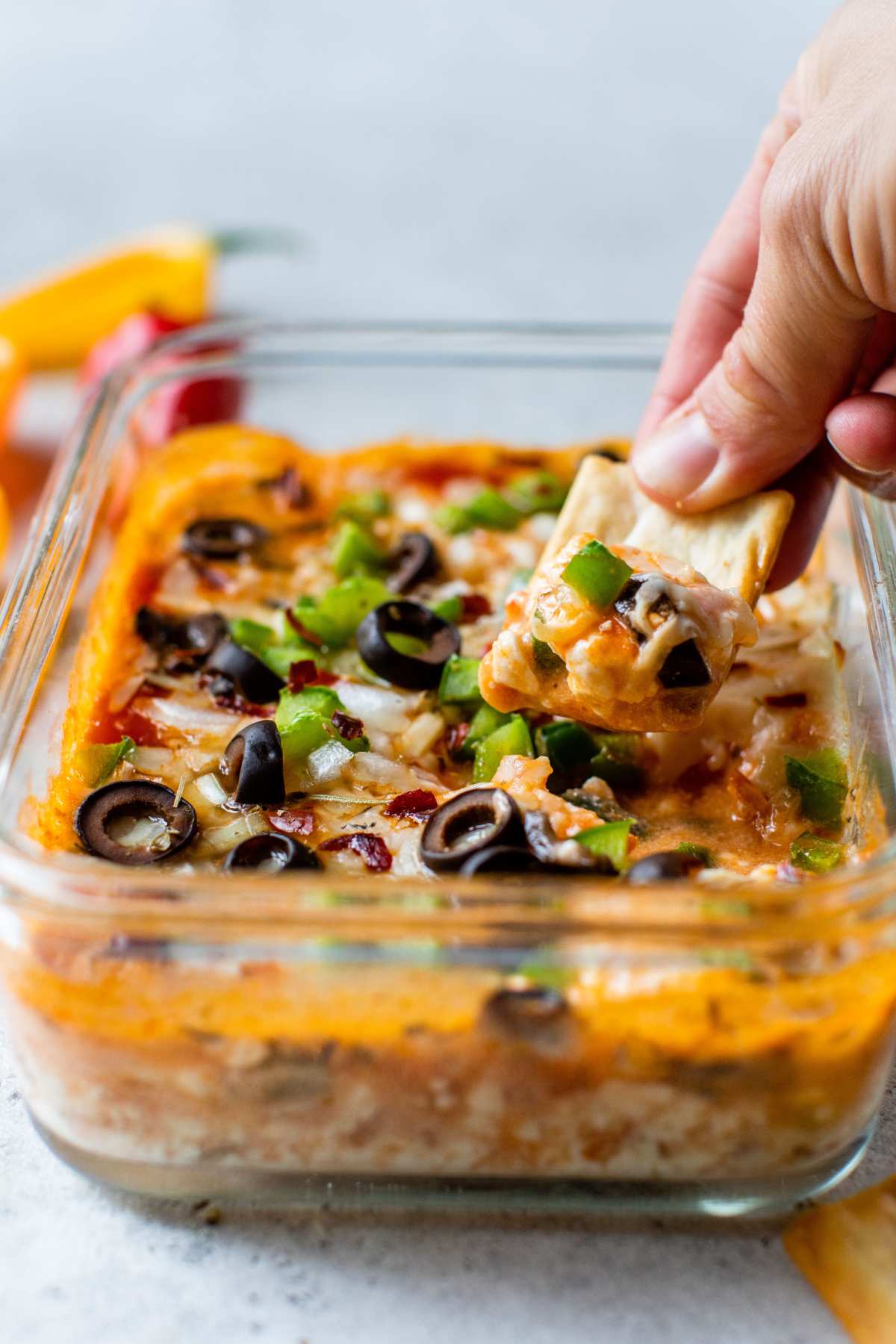 Hand dipping a chip into a cottage cheese pizza bowl.