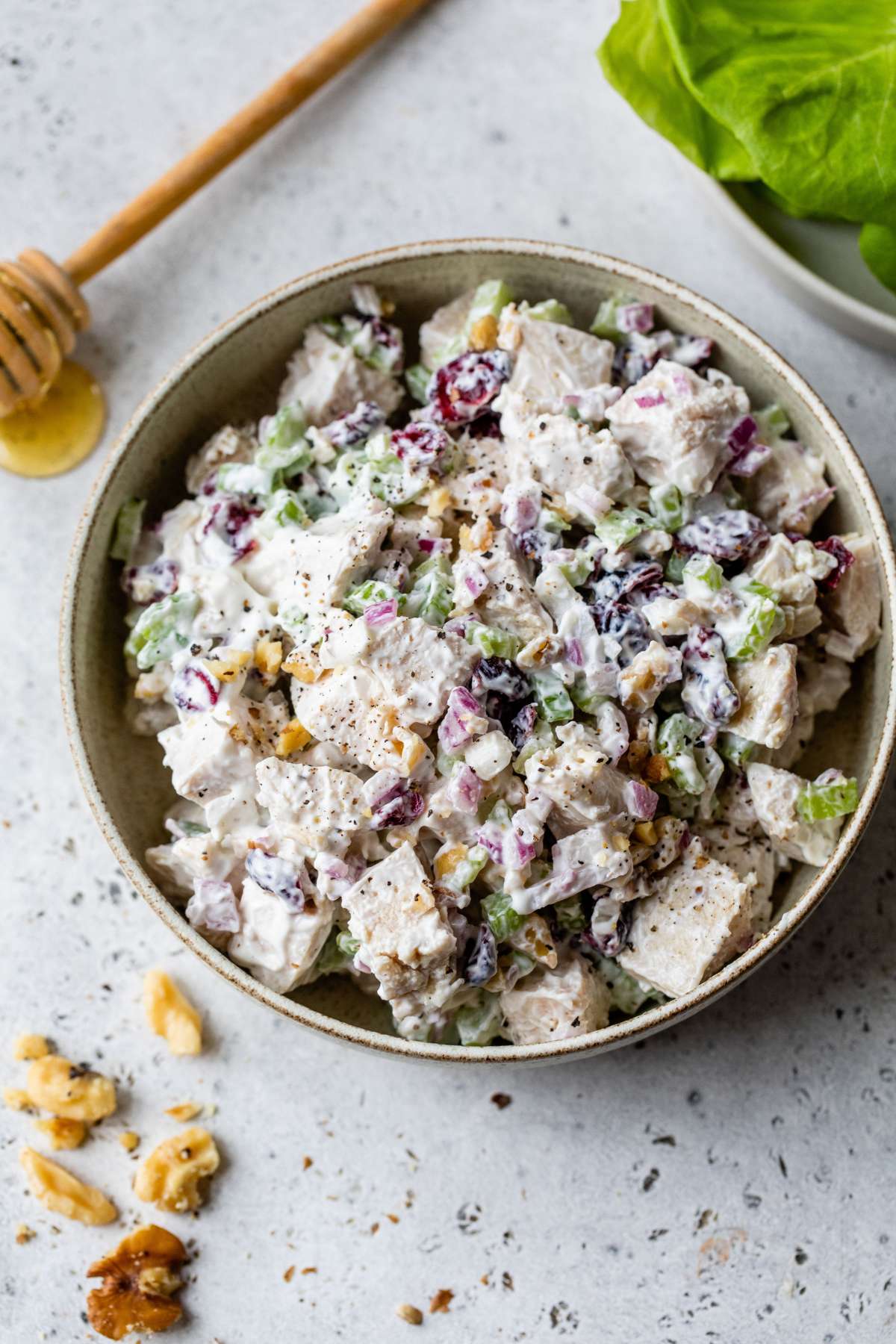 Chicken salad in a bowl near lettuce leaves.