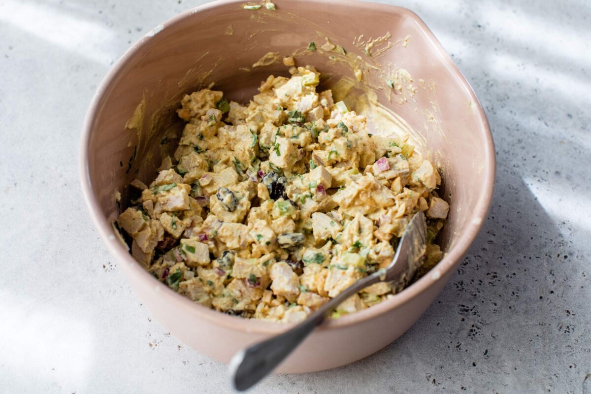 Stirring dressing with chicken salad ingredients.