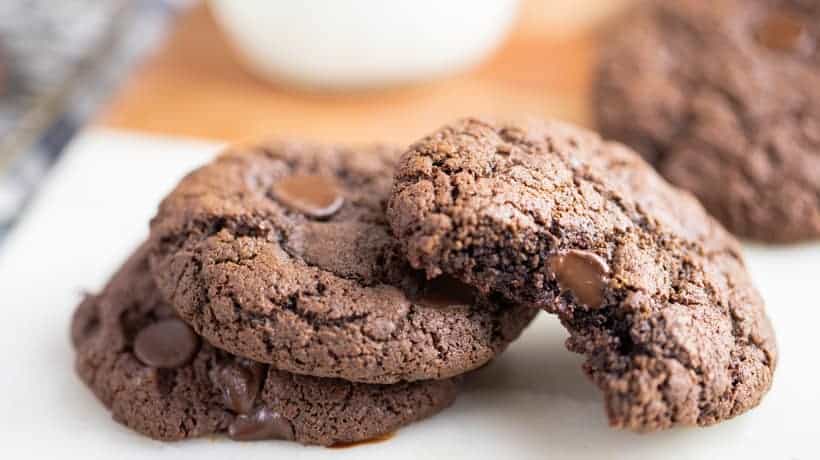double chocolate chip cookies stacked up with a cup of milk