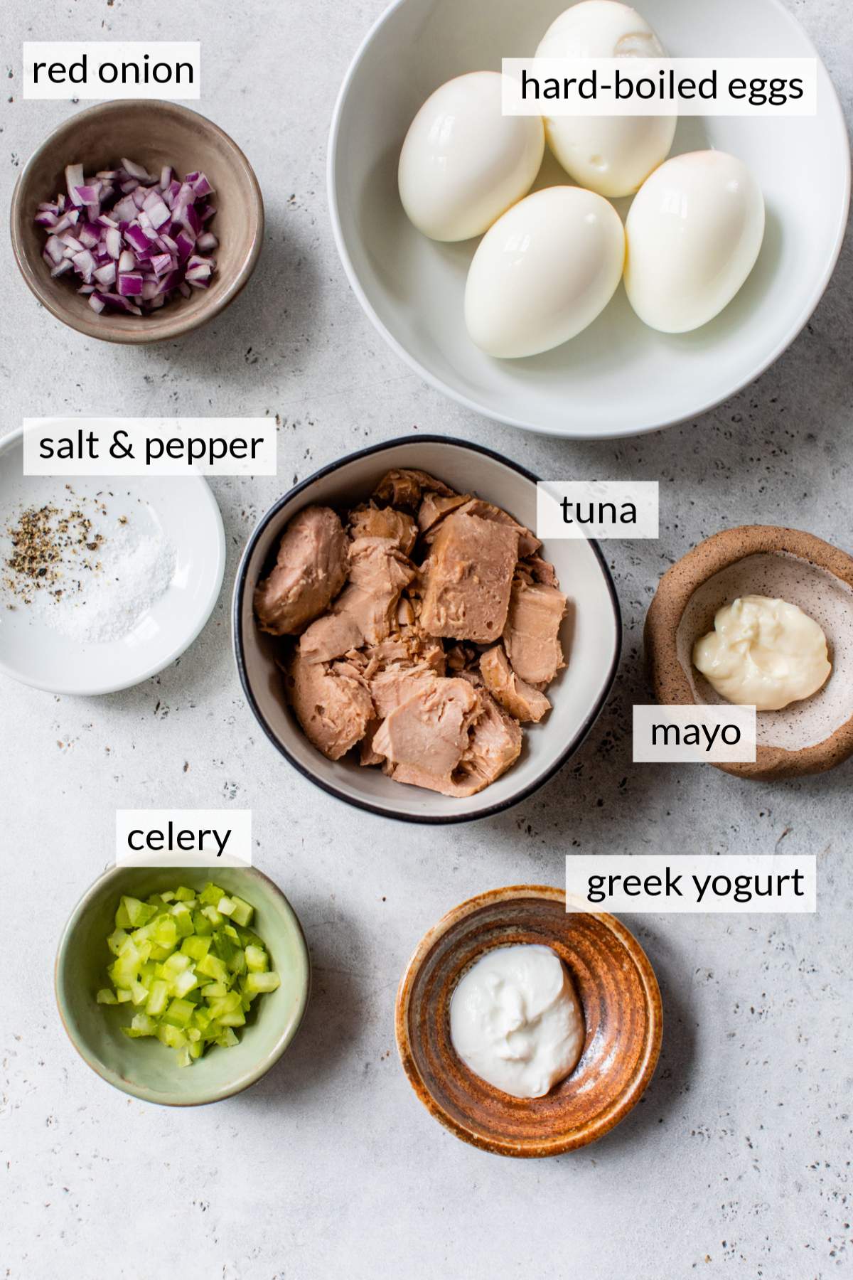 Bowls with hard-boiled eggs, tuna, red onion, celery and mayo.