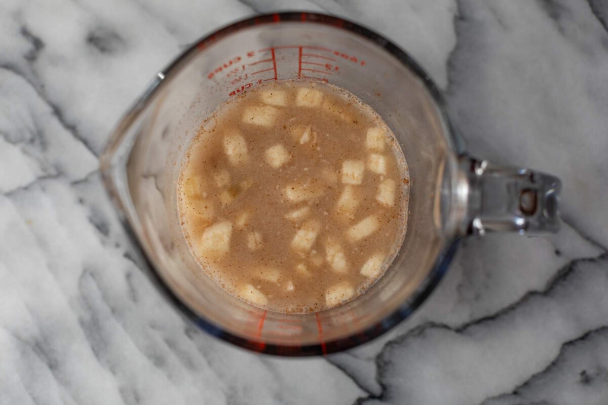 Oats, banana slices, cinnamon, sea salt, and water in a glass spouted cup.