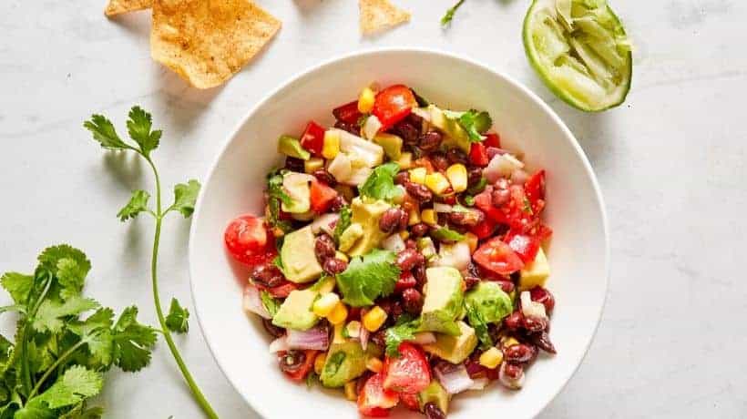 black bean salad with corn, tomatoes and avocado served with chips