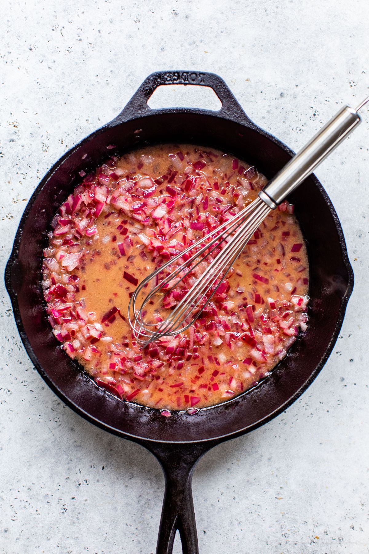 Stirring apple cider vinegar, maple syrup, dijon mustard, salt and pepper with red onion.