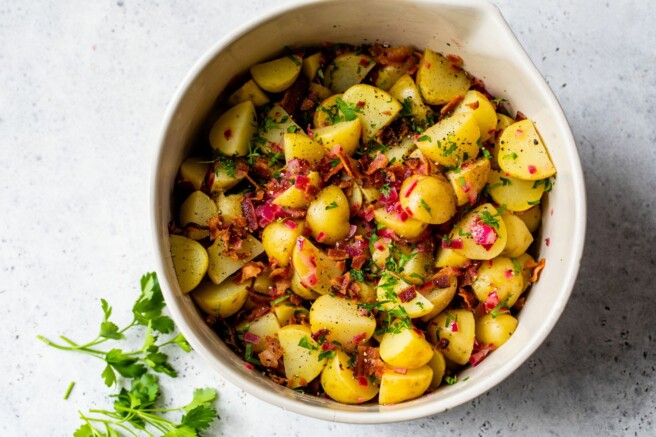 Tossing potatoes with dressing, bacon and parsley.