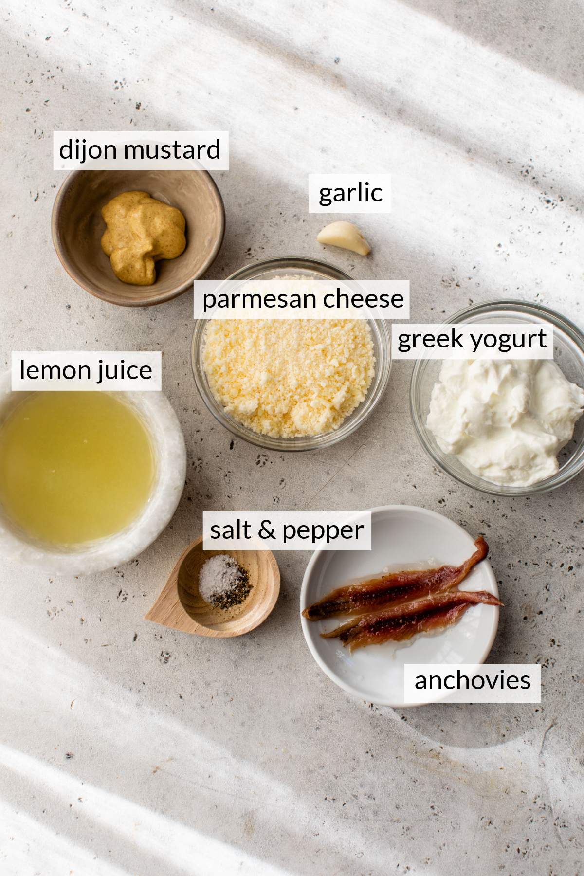 Bowls with lemon juice, anchovies, greek yogurt, parmesan cheese and dijon mustard.