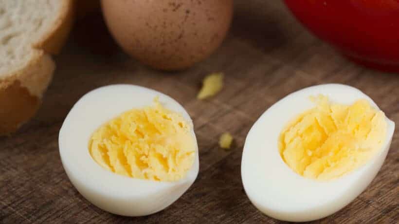 hard boiled egg slice in half on wooden cutting board