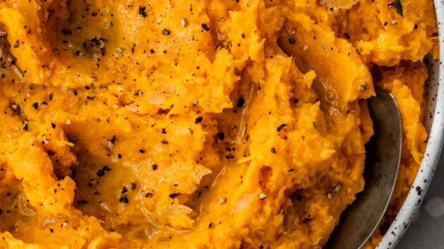 Healthy mashed sweet potatoes in a white bowl with a spoon.