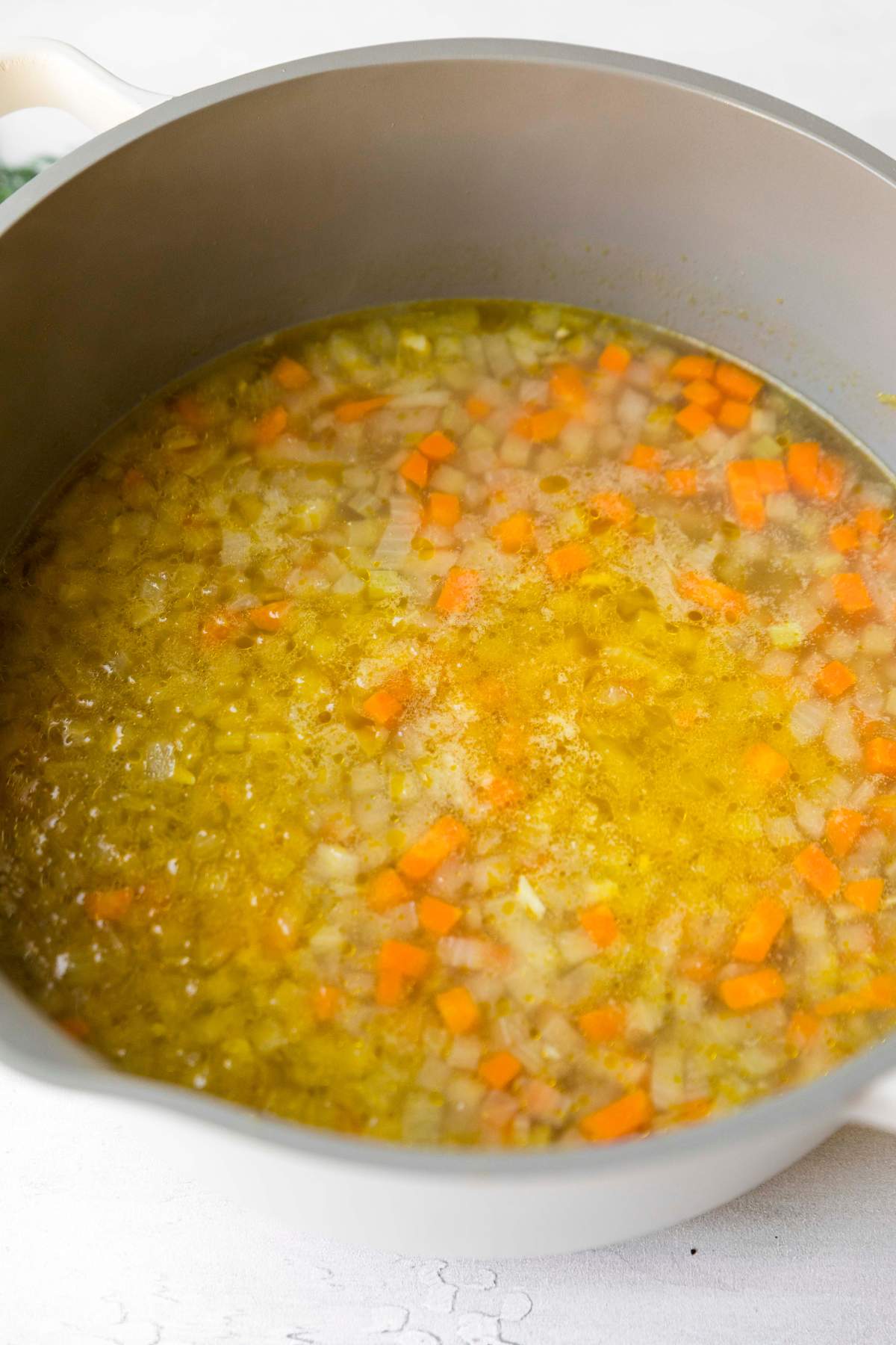 Adding broth to sautéed veggies.