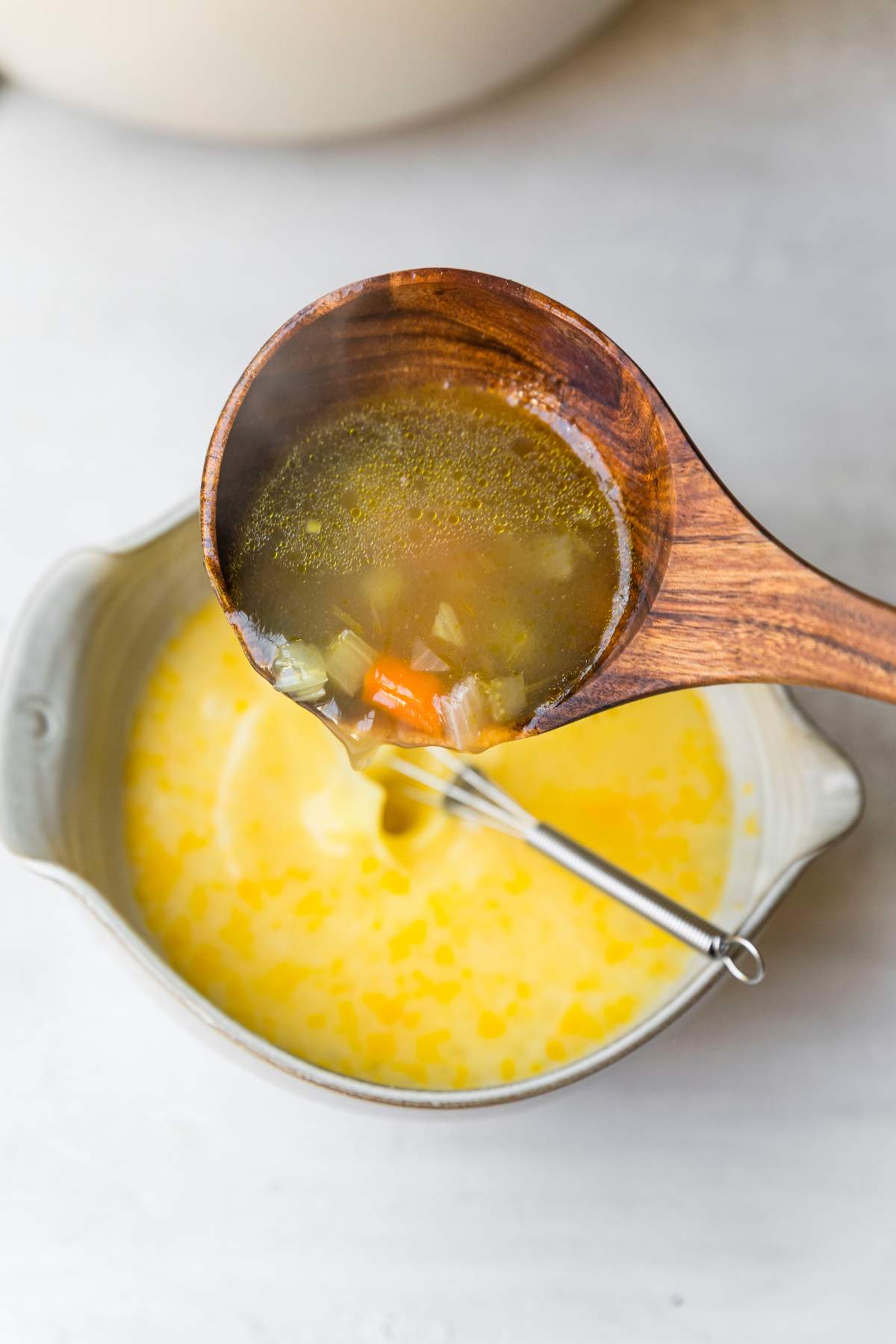Pouring soup into egg mixture.