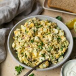 Lightened up egg salad in a bowl near slices of bread.