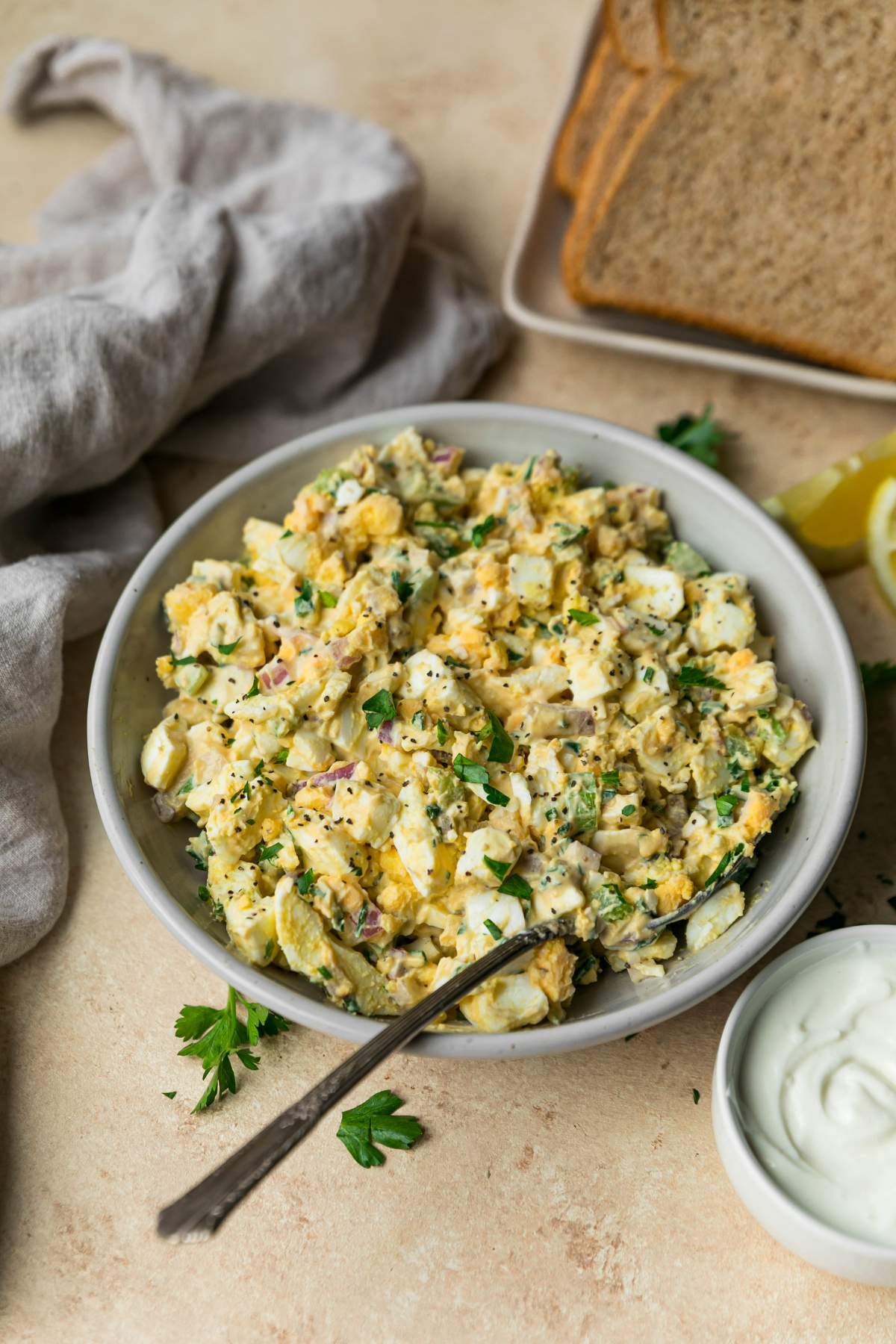 Lightened up egg salad in a bowl near slices of bread.