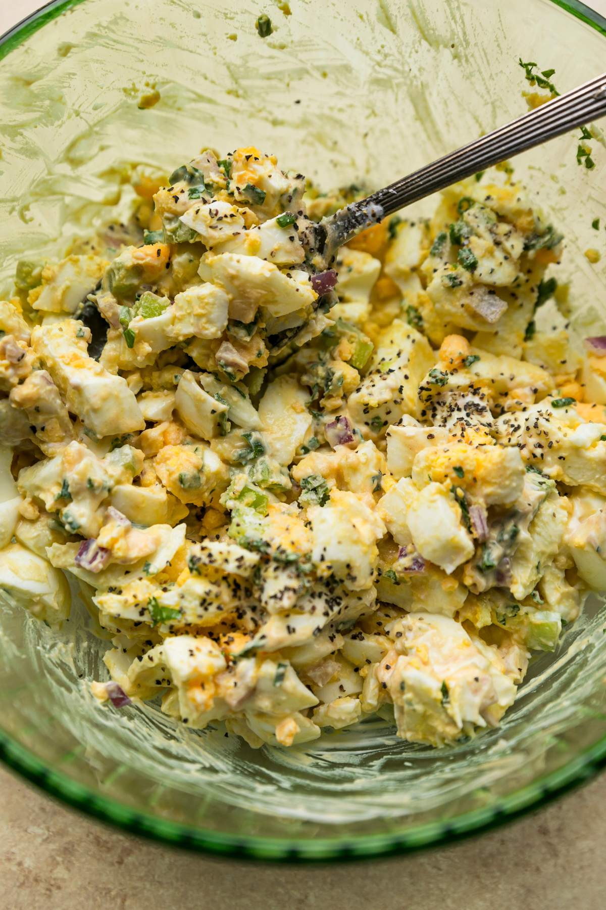 Mixing together Greek yogurt egg salad in a large bowl.