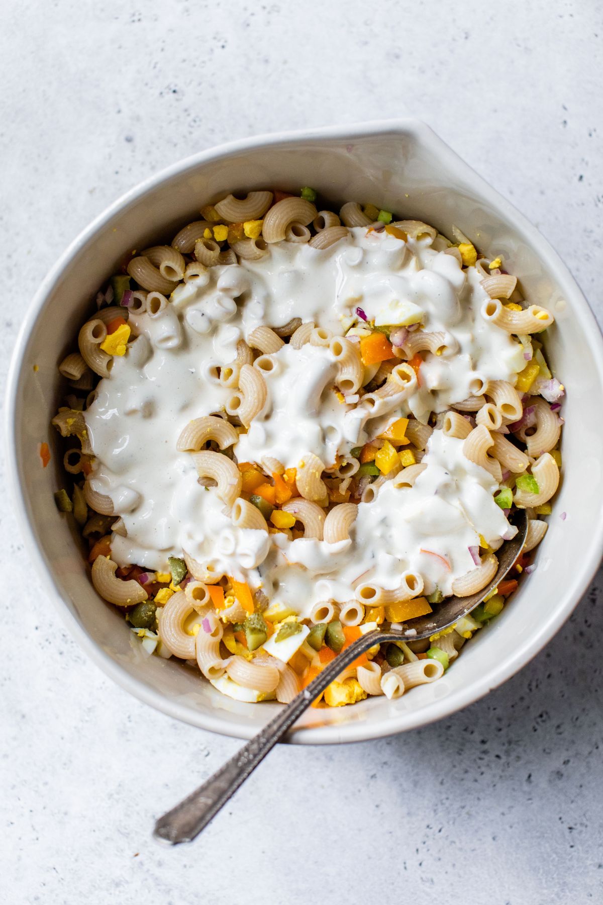 Pouring the dressing over the macaroni salad.