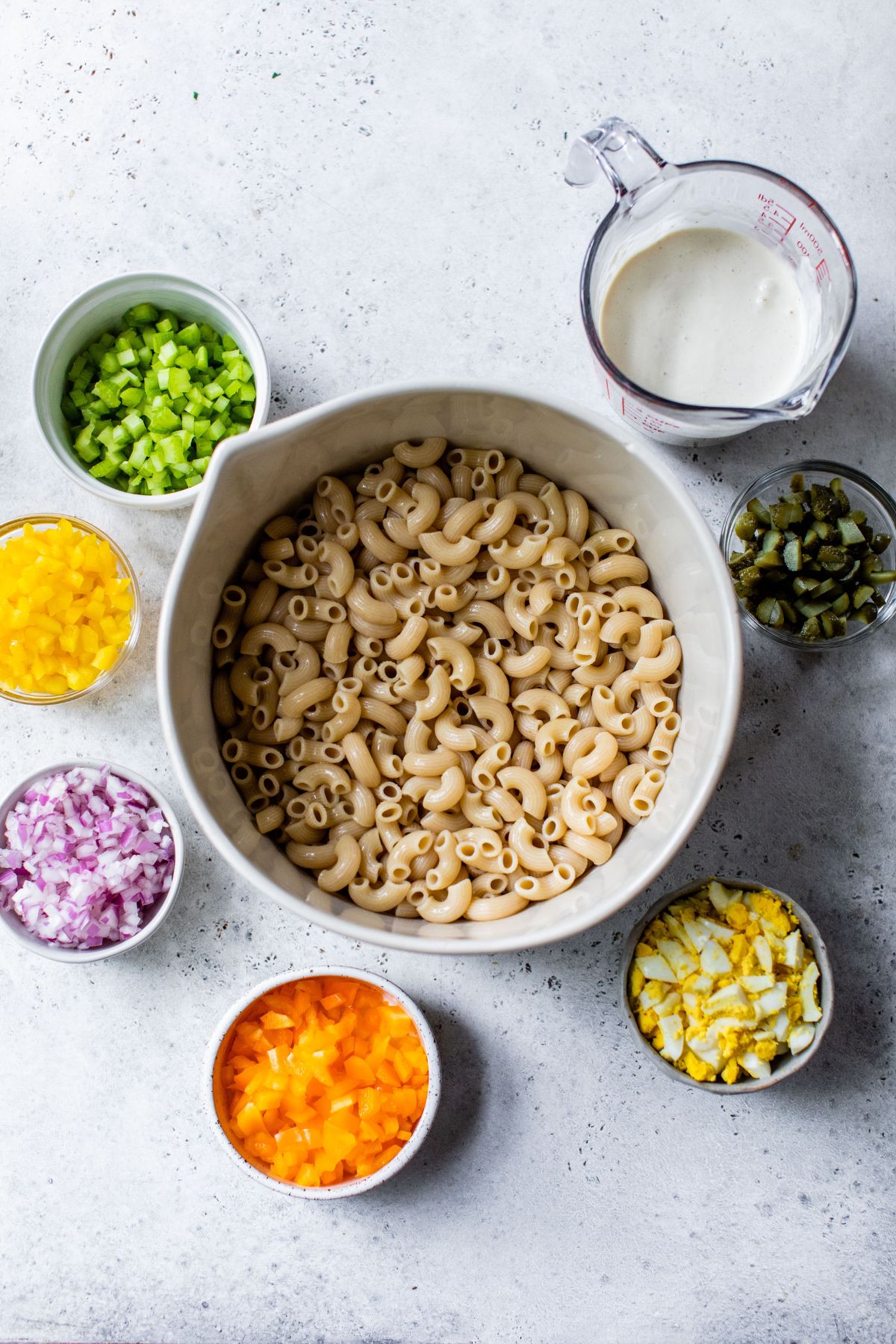 Ingredients for pasta salad divided into small bowls.