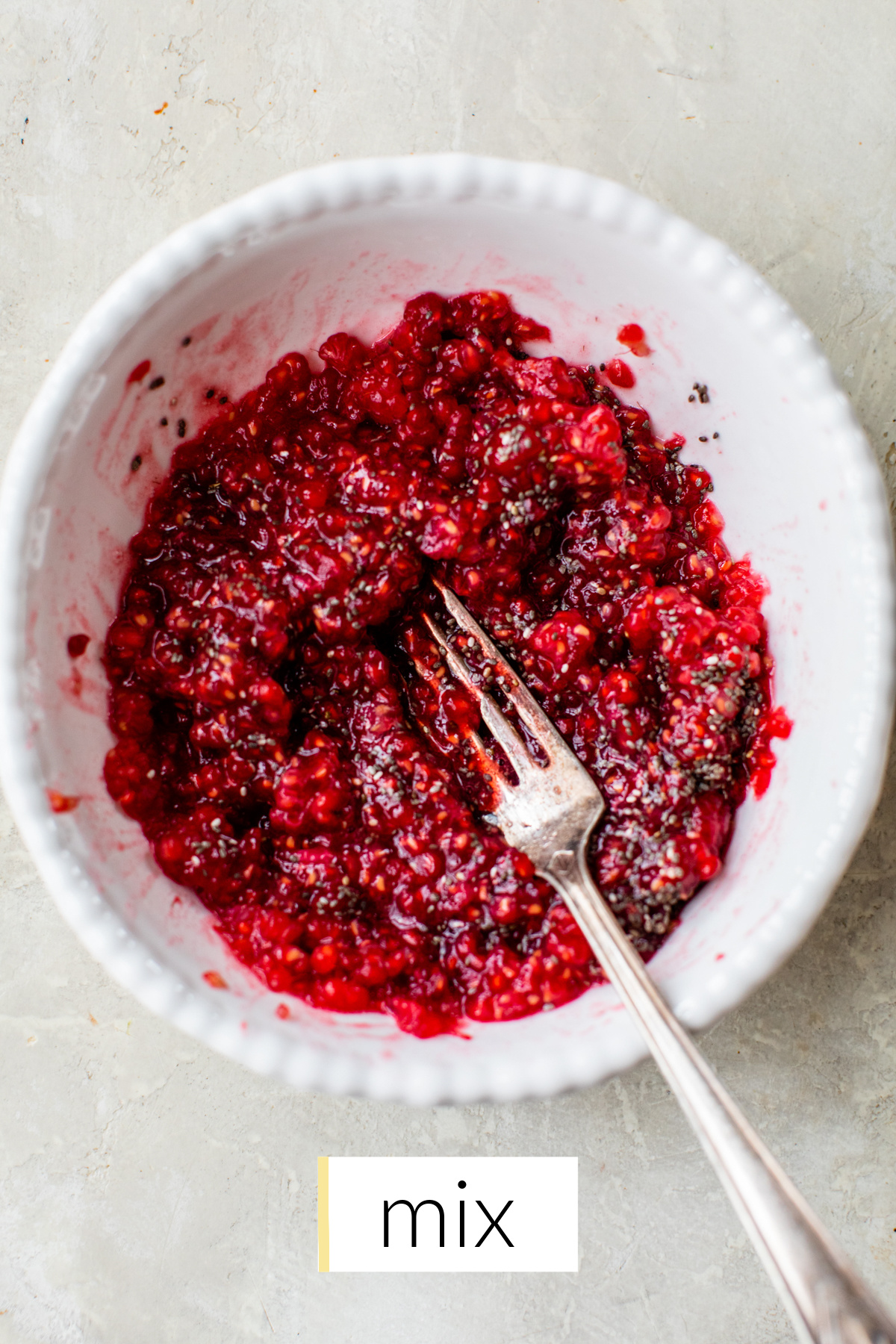 mashed raspberries and chia seeds mixed in a white bowl