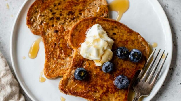 French toast on a plate topped with Greek yogurt and blueberries.