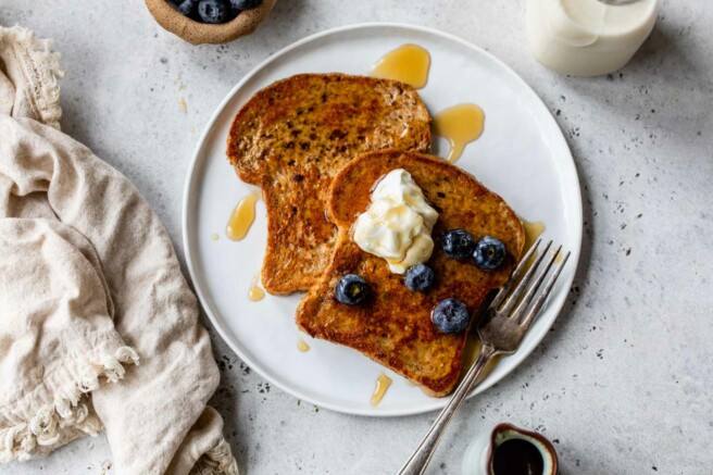French toast on a plate topped with Greek yogurt and blueberries.