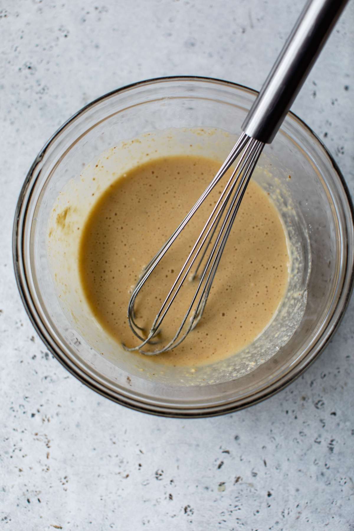 Using a whisk to mix pancake batter in a large bowl.
