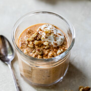 Pumpkin overnight oats in a glass jar topped with nuts and yogurt.