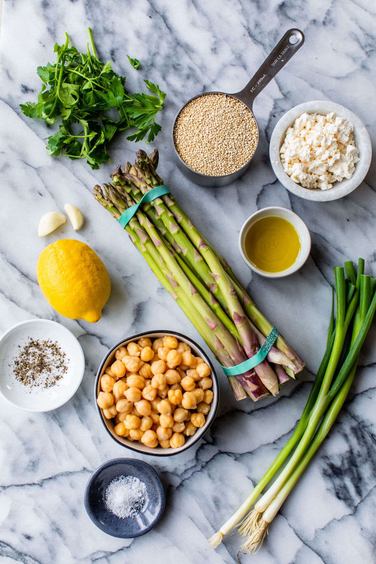 Uncooked quinoa, asparagus and feta divided into small portions.