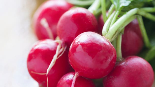 Red radish bunch with green leaves on wood chopping board