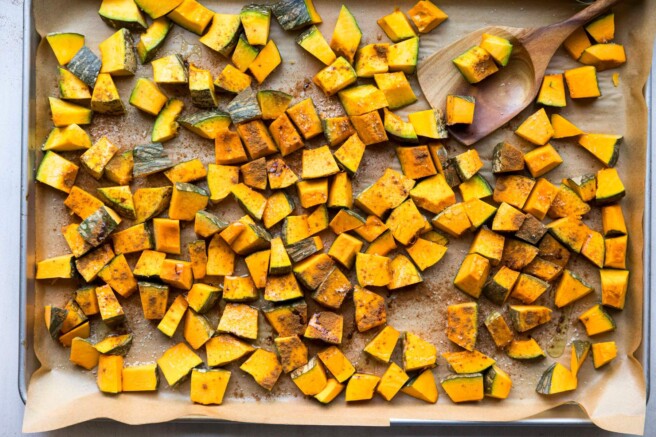 Cubed kabocha squash on a parchment lined sheet pan.