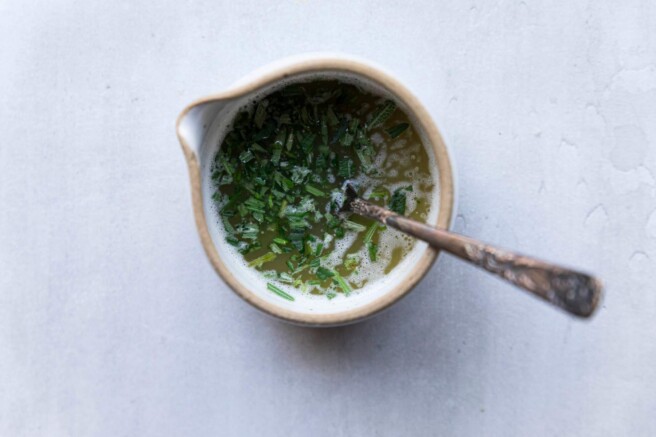 Melted butter and rosemary mixture in a small cup.