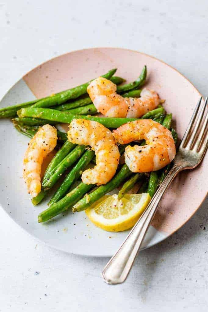 roasted shrimp and green beans served on a small plate
