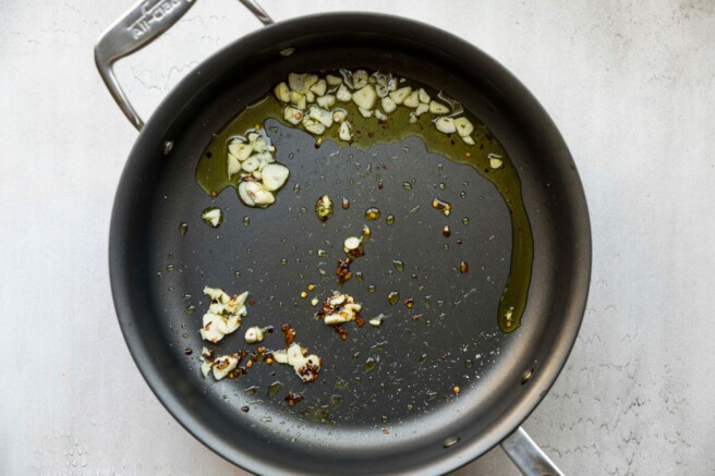 Sautéing garlic and red pepper flakes in olive oil.