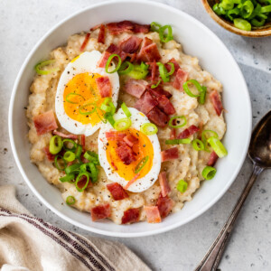 Bowl of savory oats topped with hard boiled egg and turkey bacon