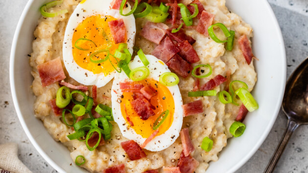 Bowl of savory oats topped with hard boiled egg and turkey bacon