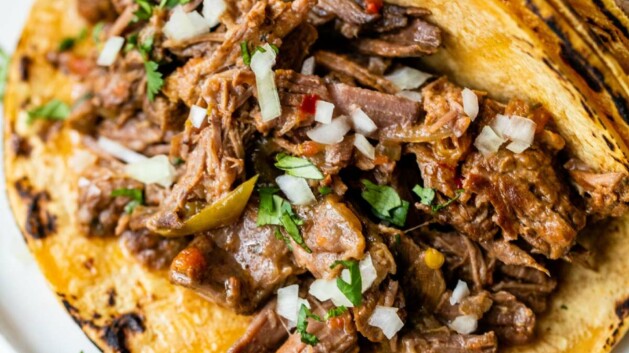 Tacos with beef, onion and jalapeño on a white plate.